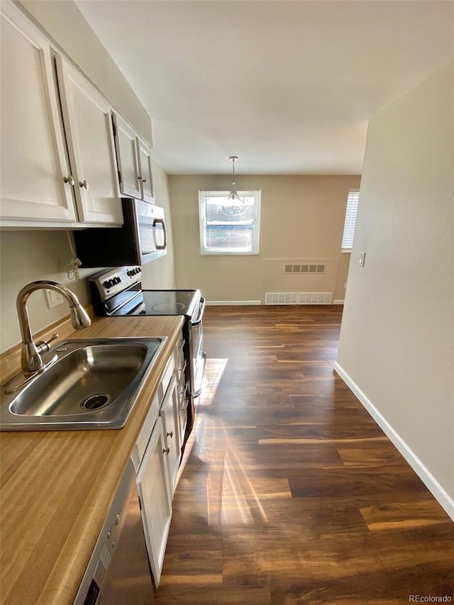 1243 Gaylord St Unit 302, Denver, CO 80206 - kitchen featuring stainless steel appliances, healthy amount of natural light, dark wood-type flooring, and pendant lighting