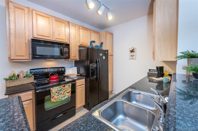 kitchen featuring light brown cabinetry, a sink, track lighting, dark stone counters, and black appliances