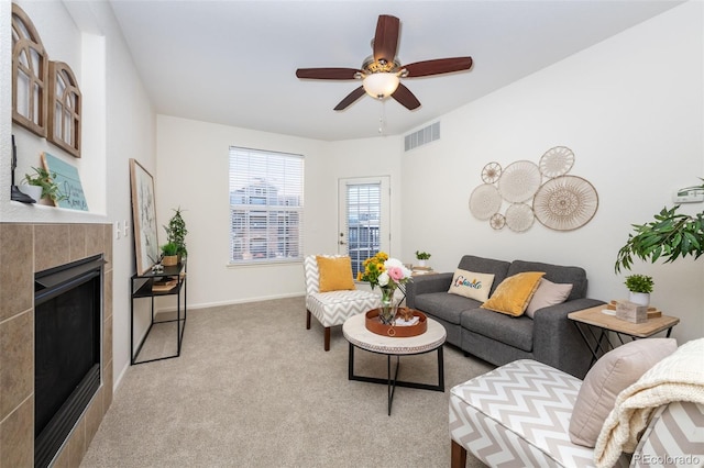 living area featuring light carpet, baseboards, visible vents, ceiling fan, and a fireplace