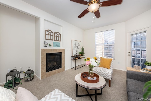 living room with ceiling fan, a tile fireplace, carpet flooring, and baseboards