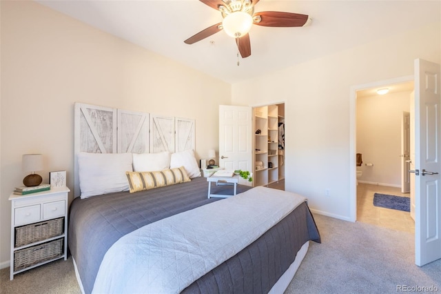 bedroom with a walk in closet, a ceiling fan, carpet flooring, ensuite bath, and baseboards