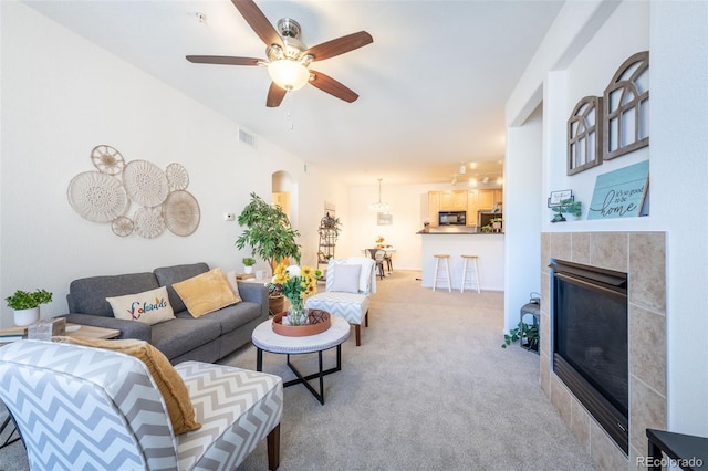 living room with light carpet, ceiling fan, visible vents, and a tiled fireplace