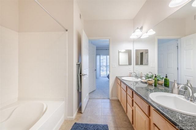 bathroom with baseboards, double vanity, a sink, and tile patterned floors