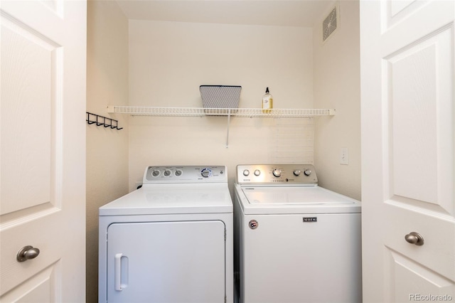 clothes washing area featuring laundry area, visible vents, and washing machine and clothes dryer