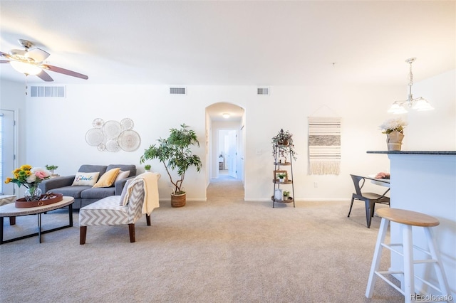 living room with arched walkways, visible vents, and light carpet