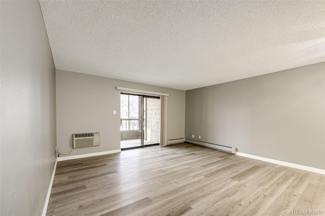 empty room with a wall mounted air conditioner, light hardwood / wood-style flooring, a baseboard heating unit, and a textured ceiling