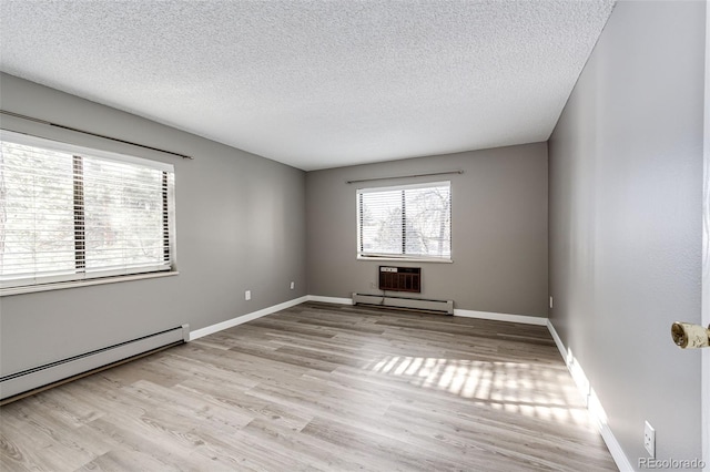 spare room featuring light hardwood / wood-style floors, a baseboard radiator, and a textured ceiling