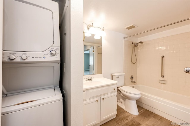 full bathroom featuring wood-type flooring, vanity, toilet, stacked washer and clothes dryer, and bathtub / shower combination