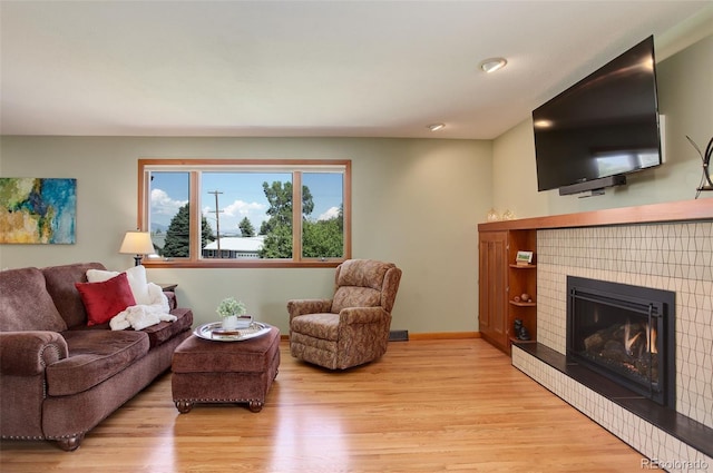 living room featuring a tiled fireplace and light hardwood / wood-style floors