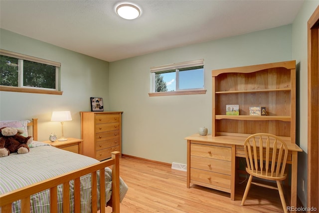 bedroom featuring built in desk and light wood-type flooring