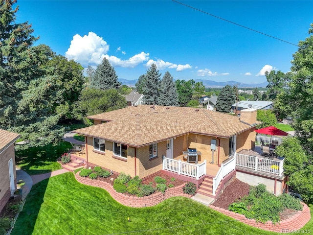 9350 Grandview Ave, Arvada, CO 80002 - view of front facade featuring a front lawn, roof with shingles, a deck with mountain view, and brick siding