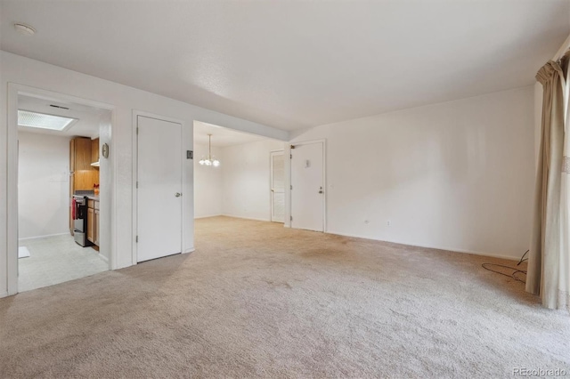 carpeted spare room featuring a chandelier