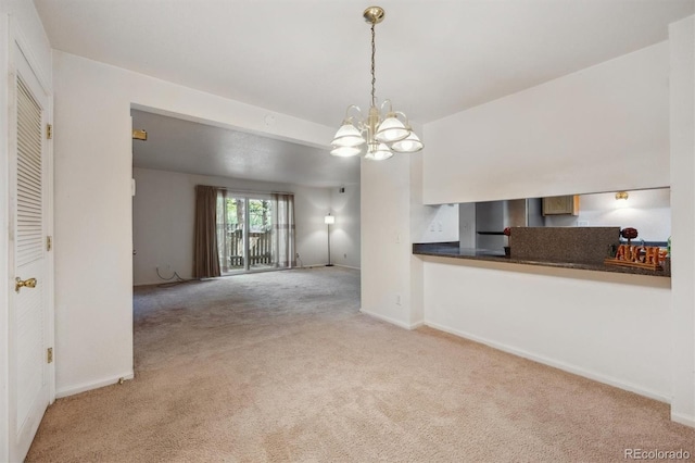 unfurnished living room with carpet floors, a chandelier, and baseboards