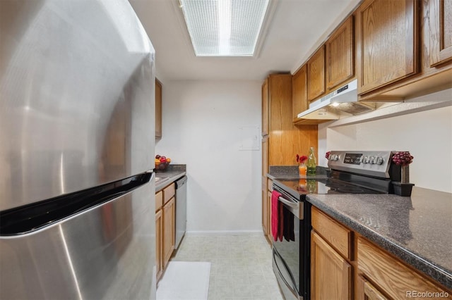 kitchen with stainless steel appliances, under cabinet range hood, dark countertops, light flooring, and brown cabinets