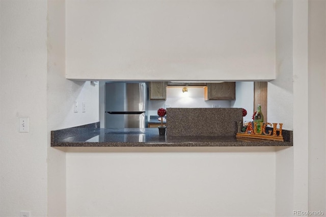 kitchen with freestanding refrigerator, a peninsula, and dark countertops