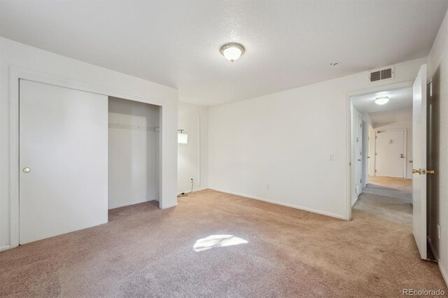 unfurnished bedroom featuring light carpet and a closet