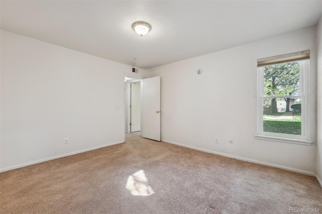 empty room featuring light carpet and baseboards
