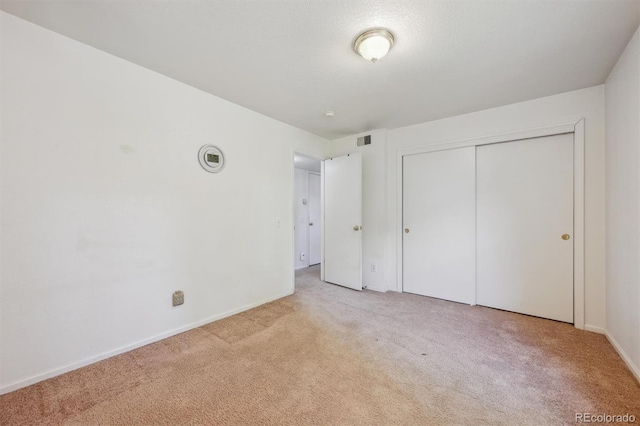 unfurnished bedroom with carpet flooring, baseboards, and a closet