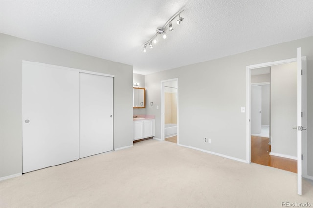 4127 S Lewiston Cir, Aurora, CO 80013 - unfurnished bedroom featuring a closet, light colored carpet, a textured ceiling, ensuite bathroom, and baseboards