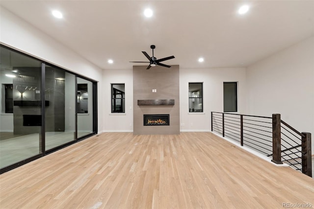 unfurnished living room featuring ceiling fan, a fireplace, and light hardwood / wood-style floors