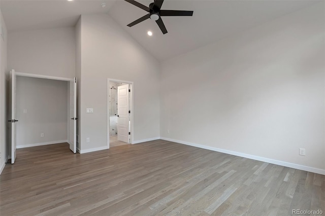 unfurnished bedroom featuring high vaulted ceiling, ensuite bathroom, ceiling fan, and light wood-type flooring