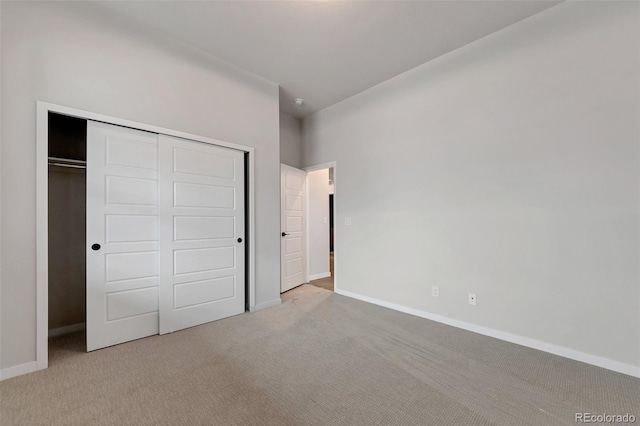 unfurnished bedroom with light colored carpet and a closet