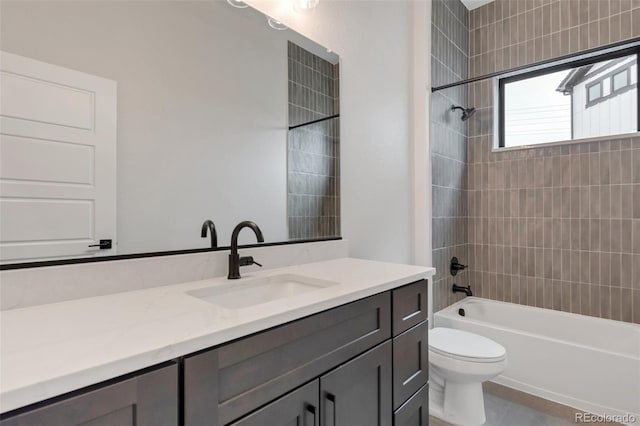 full bathroom with tile patterned flooring, tiled shower / bath, vanity, and toilet