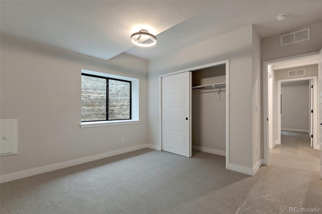 unfurnished bedroom with light carpet, a textured ceiling, and a closet