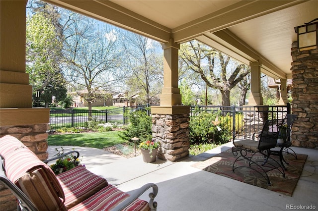 view of patio featuring fence and a porch
