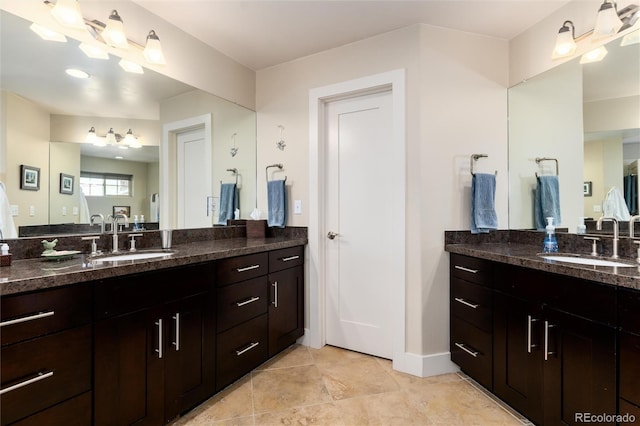 full bath with a sink, two vanities, baseboards, and tile patterned floors