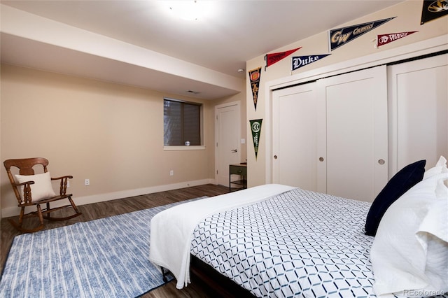 bedroom with wood finished floors, a closet, and baseboards