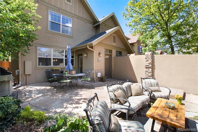 rear view of house with a patio, stucco siding, fence, an outdoor hangout area, and stone siding