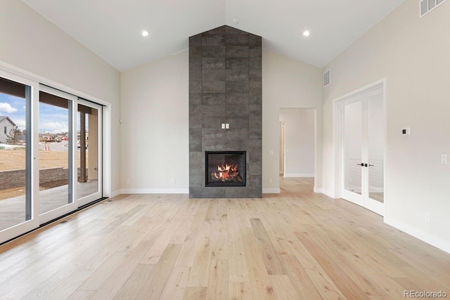 unfurnished living room featuring light hardwood / wood-style floors, a fireplace, and high vaulted ceiling