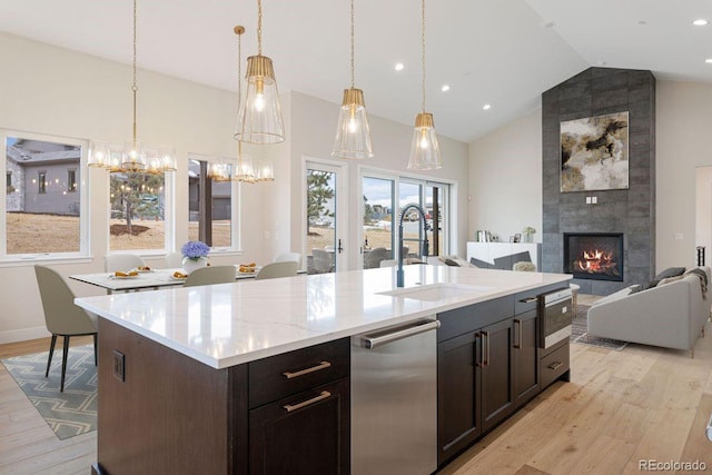 kitchen with a tile fireplace, sink, lofted ceiling, and a center island with sink