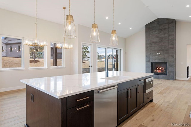 kitchen featuring a center island with sink, sink, a tile fireplace, and built in microwave