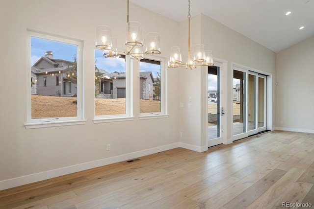 unfurnished dining area with light wood-type flooring and an inviting chandelier