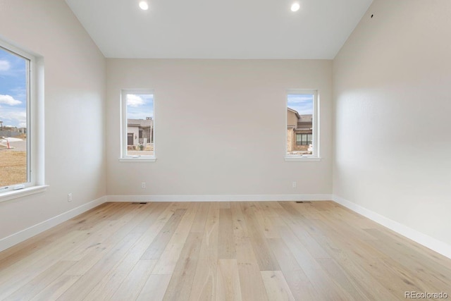 empty room with light hardwood / wood-style floors and vaulted ceiling