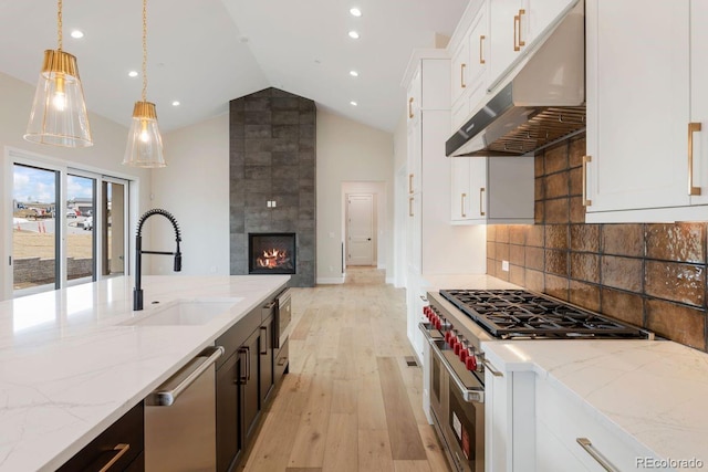 kitchen with light stone counters, stainless steel appliances, sink, pendant lighting, and white cabinetry