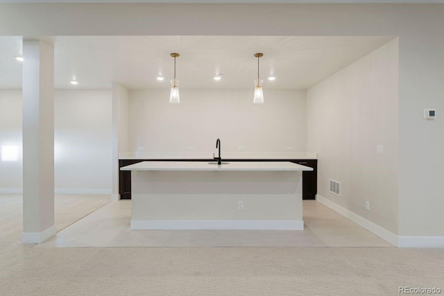 kitchen featuring sink, hanging light fixtures, and an island with sink