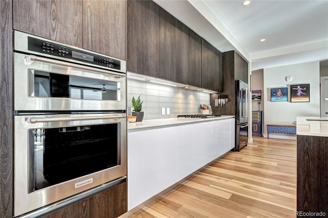 kitchen with light wood-style flooring, modern cabinets, appliances with stainless steel finishes, and dark brown cabinets