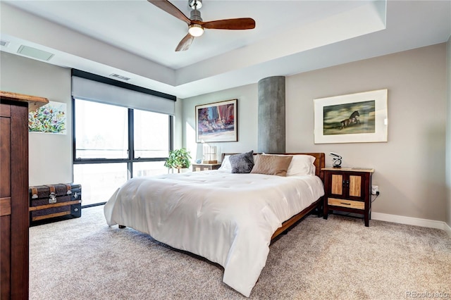 carpeted bedroom with baseboards, visible vents, ceiling fan, and a raised ceiling