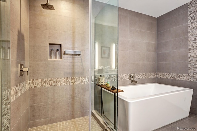 bathroom with tile patterned flooring, plus walk in shower, and tile walls