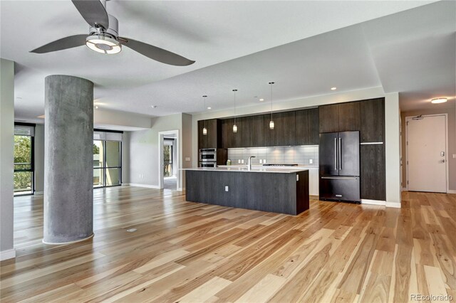4200 W 17th Ave Unit 235, Denver, CO 80204 - kitchen featuring light wood finished floors, open floor plan, light countertops, high end refrigerator, and dark brown cabinets