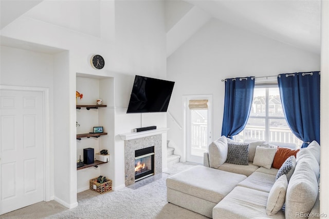 living room featuring a tiled fireplace, high vaulted ceiling, and light carpet