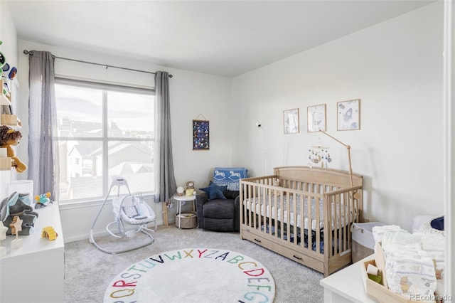 carpeted bedroom featuring multiple windows and a nursery area