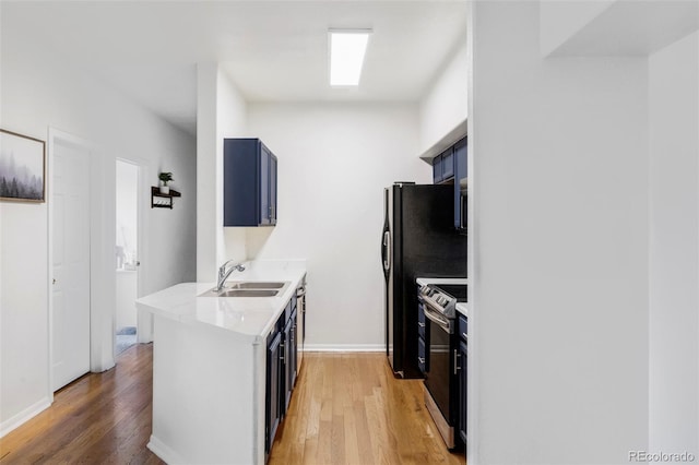 kitchen with blue cabinetry, sink, stainless steel range with electric cooktop, and light wood-type flooring