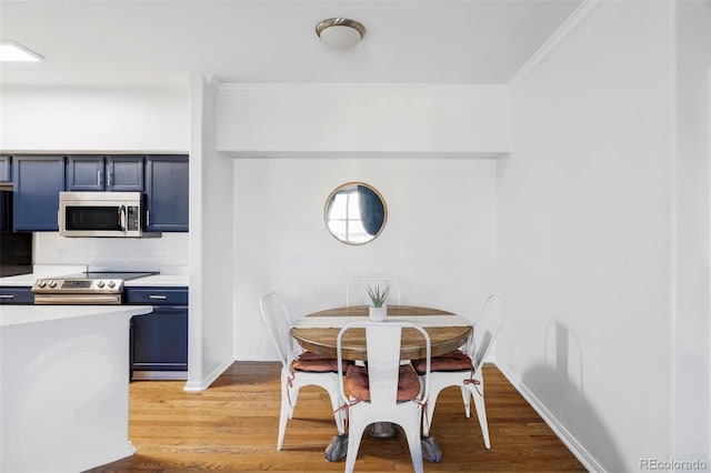 dining room with ornamental molding and light hardwood / wood-style flooring