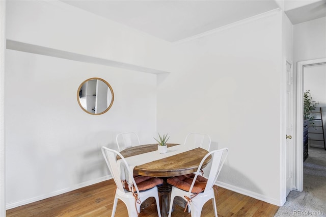 dining room with hardwood / wood-style flooring and crown molding