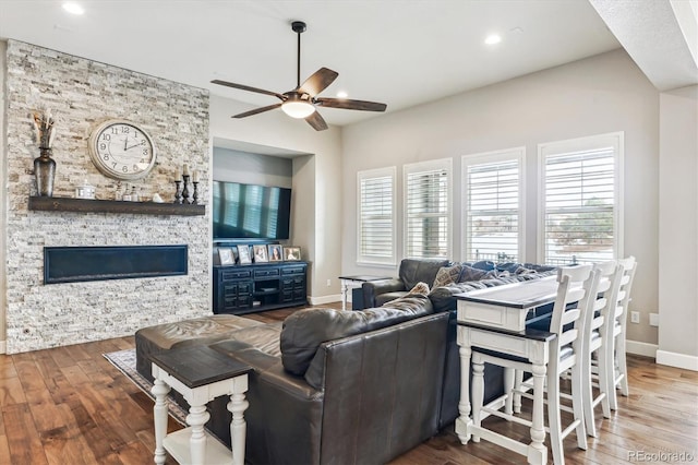 living room featuring a stone fireplace, plenty of natural light, and hardwood / wood-style floors