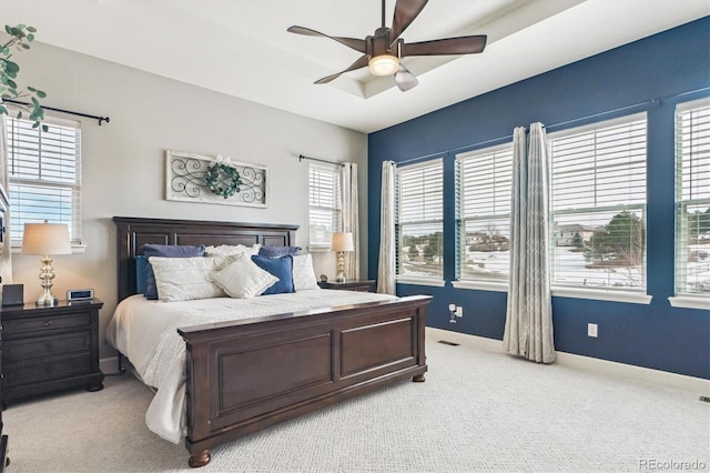 bedroom with a tray ceiling, light colored carpet, and ceiling fan